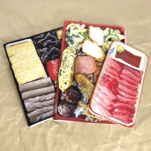 「うちなーちょーめん」3冊のノートが机に置かれている。表紙に沖縄の重箱、具だくさんの弁当、マグロの刺身が印刷されている。